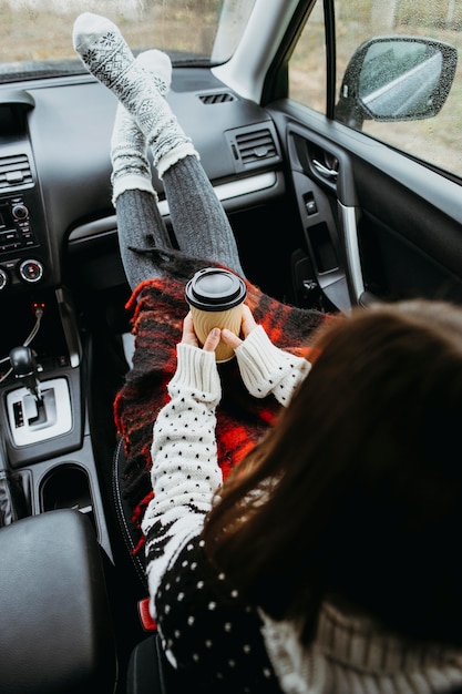 Mujer de vista trasera sentada en un coche con una taza de café