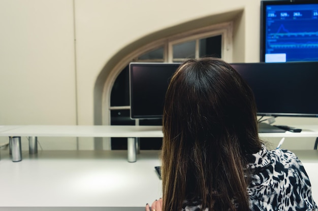 Mujer de vista trasera sentada frente al espacio de copia de la computadora