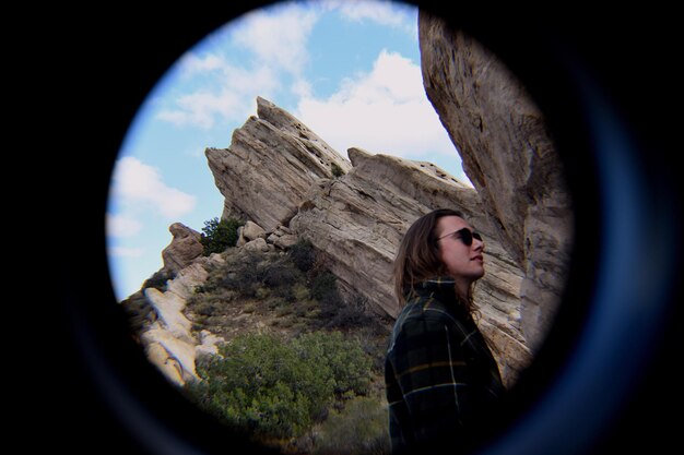 Foto mujer vista a través de un círculo contra las rocas
