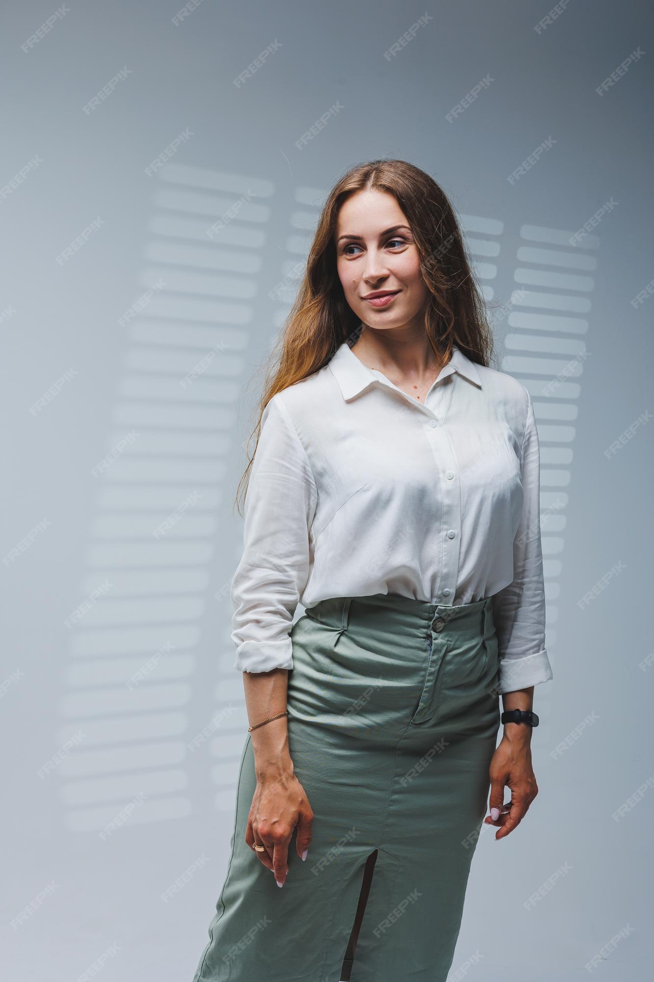 Una mujer viste blusa blanca y una falda sobre fondo gris emociones en el rostro de una mujer mujer elegante mirada positiva modelo en ropa casual verano primavera u otoño