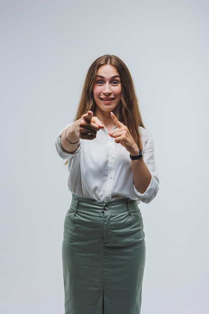 Una mujer viste una blusa blanca y una falda sobre un fondo gris emociones en el rostro de una mujer Mujer elegante mirada positiva Modelo en ropa casual Verano primavera u otoño mirada callejera