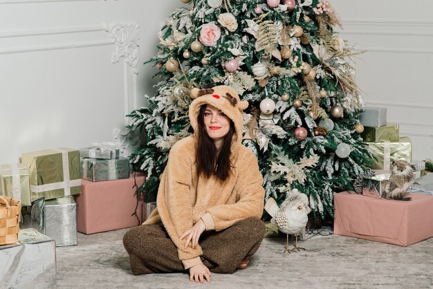 Mujer vistiendo el árbol de Navidad, sonriendo, sentado en el interior de año nuevo