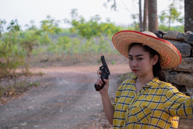 Mujer vistiendo una camisa amarilla mano sujetando una vieja pistola revólver la granja Niña con una pistola