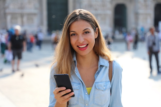 Mujer vistiendo camisa enviando mensajes de texto en el teléfono inteligente.