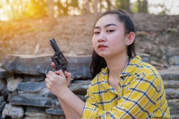 Mujer vistiendo una camiseta amarilla mano sujetando una vieja pistola revólver en la granja