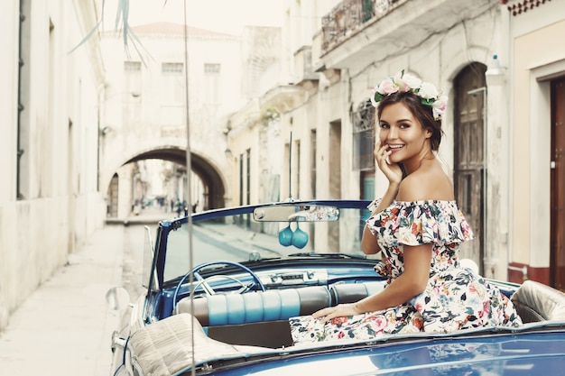 Mujer vistiendo un hermoso vestido y coche convertible retro en la ciudad de La Habana.