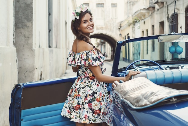 Mujer vistiendo un hermoso vestido y coche convertible retro en la ciudad de La Habana.