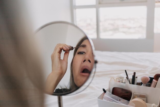 Mujer vistiendo maquillaje en el espejo con herramientas y equipos.