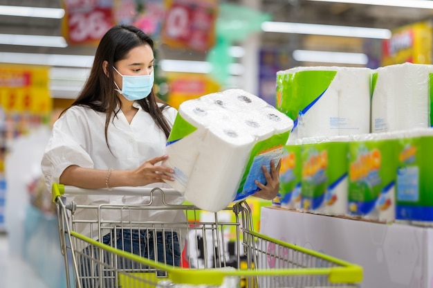 Mujer vistiendo mascarilla comprando en el supermercado