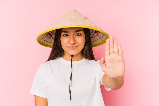 Mujer vistiendo un sombrero vietnamita mostrando la señal de stop, impidiéndole