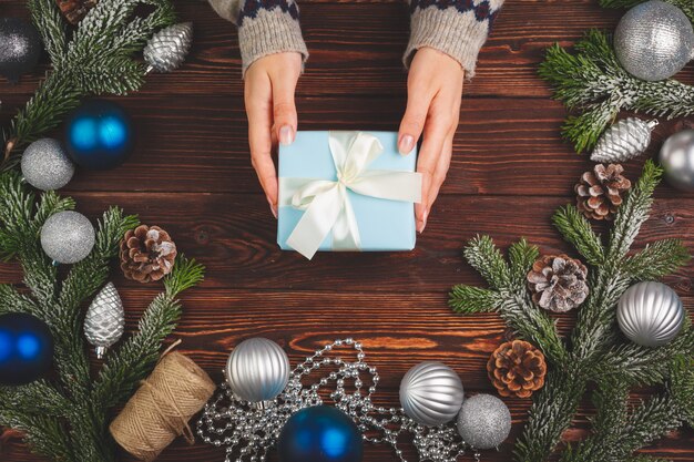 Mujer vistiendo suéter y sosteniendo un regalo decorado