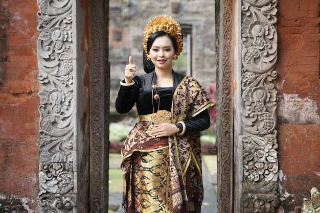 Mujer vistiendo traje tradicional balinés con pulgares arriba