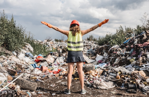 Mujer voluntaria ayuda a limpiar el campo de basura plástica. Día de la tierra y ecología.