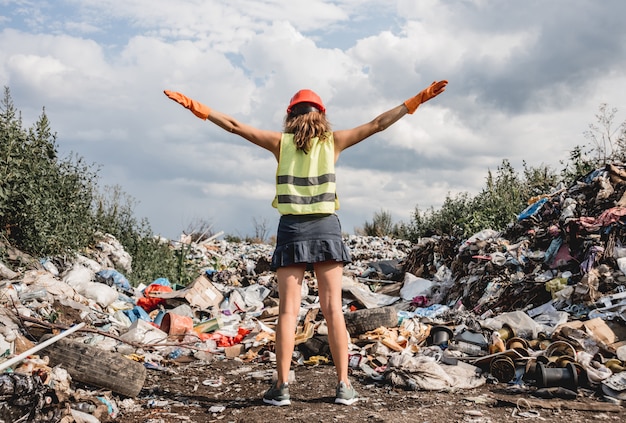 Mujer voluntaria ayuda a limpiar el campo de basura plástica. Día de la tierra y ecología.