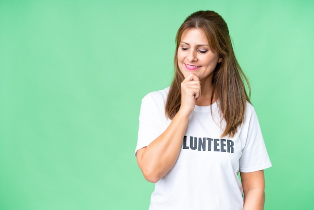 Foto mujer voluntaria de mediana edad sobre un fondo aislado mirando hacia un lado y sonriendo