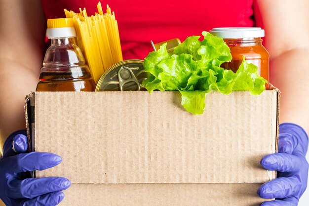 Una mujer voluntaria sostiene una caja de donación con alimentos.