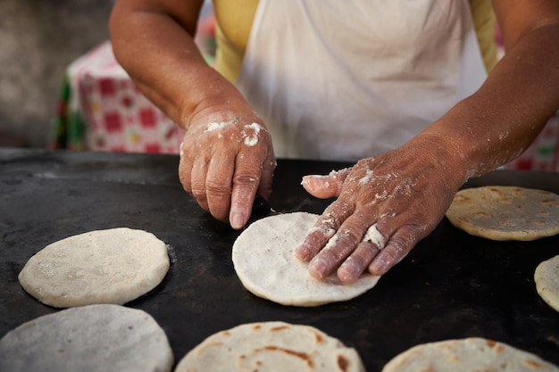 Foto mujer volviendo una tortilla de maíz con una espátula en una parrilla caliente