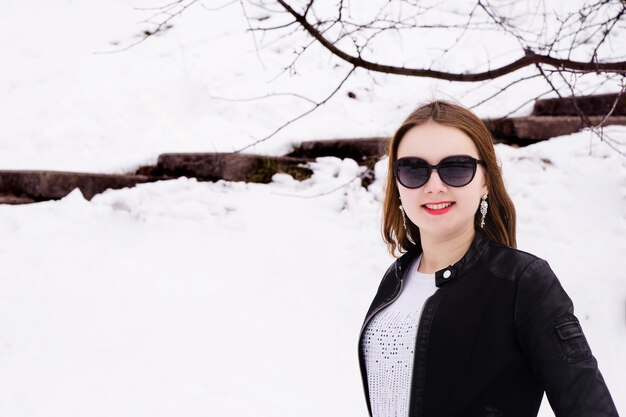 Foto mujer en winter park en gafas de sol y chaqueta