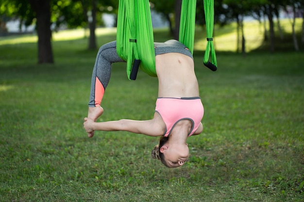 Mujer de yoga antigravedad haciendo ejercicios de yoga en el parque