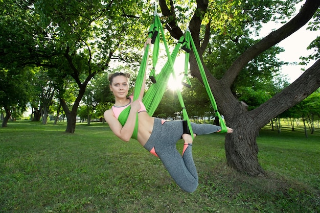 Mujer de yoga antigravedad haciendo ejercicios de yoga en el parque