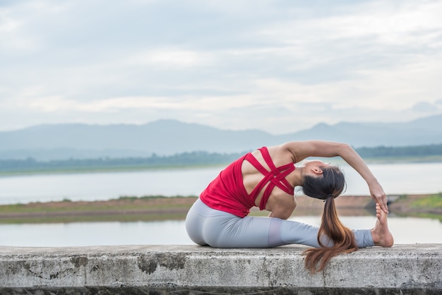 Mujer de la yoga que hace ejercicio en el lago.