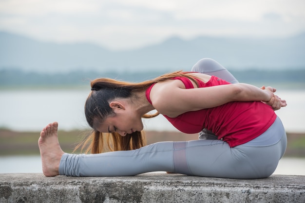 Mujer de la yoga que hace ejercicio en el lago.