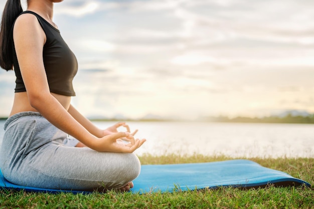 Mujer Yoga sentada cerca de la puesta de sol de la naturaleza del río