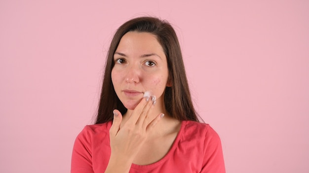 Mujer de Yong lavándose la cara con espuma en rosa