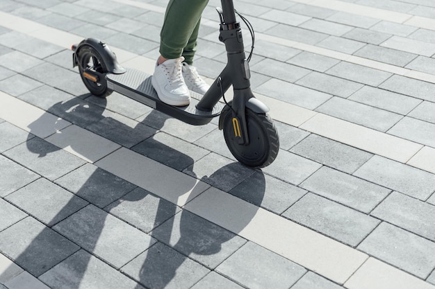 Mujer en zapatillas blancas de pie en scooter eléctrico