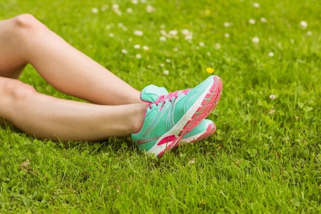 Mujer en zapatillas de deporte tumbado en la hierba