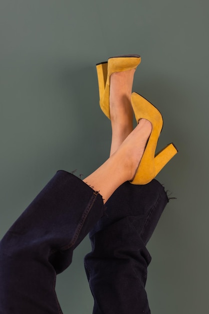 Mujer con zapatos elegantes sobre fondo amarillo.