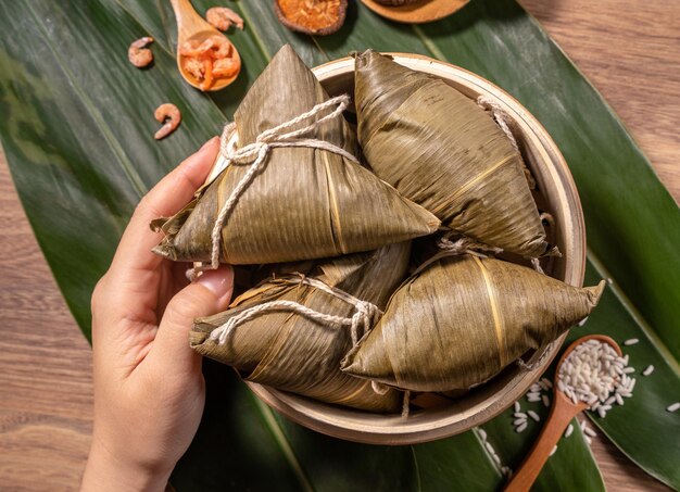 Mujer Zongzi comiendo albóndigas de arroz al vapor en la mesa de madera comida en el festival del barco del dragón duanwu concepto primer plano copia espacio vista superior plano