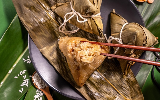 Mujer zongzi comiendo albóndigas de arroz al vapor en la mesa verde comida de fondo en el festival del bote del dragón duanwu concepto primer plano copia espacio vista superior plano