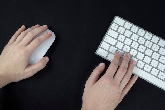 Mujer zurda sostiene un mouse de computadora en su mano izquierda teclado blanco y plateado