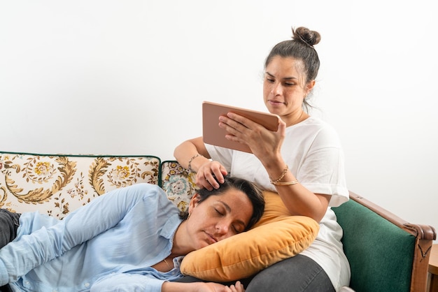 Mujeres acariciando la cabeza de su pareja mientras duerme en el sofá