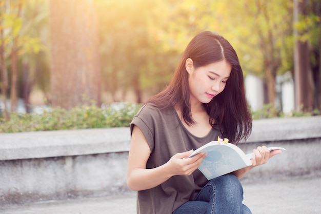 Las mujeres adolescentes asiáticas que leen la felicidad y la sonrisa del libro disfrutan de la educación en universidad.