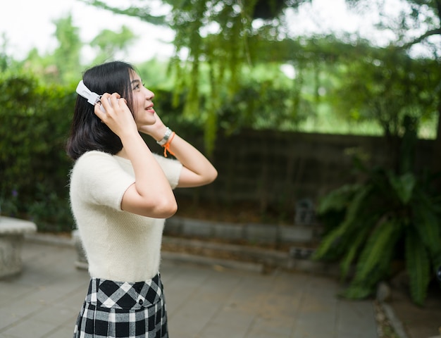 Las mujeres adolescentes escuchan la música por auriculares en el exterior