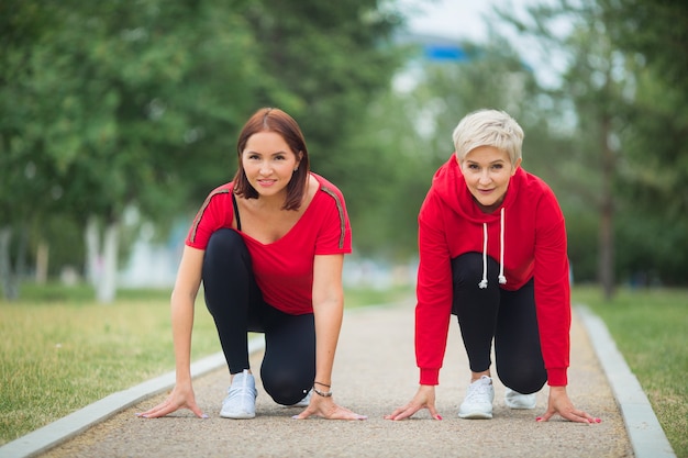 Mujeres adultas en ropa deportiva preparándose para trotar en el parque