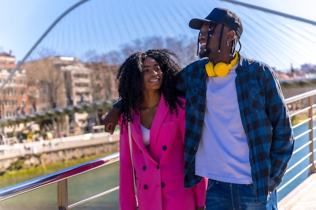 Mujeres afroamericanas jóvenes en el estilo de vida de la ciudad de amigos caminando abrazados