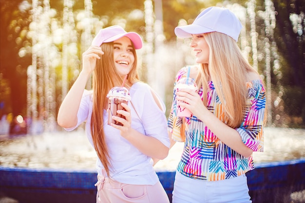 Mujeres alegres con bebidas cerca de la fuente