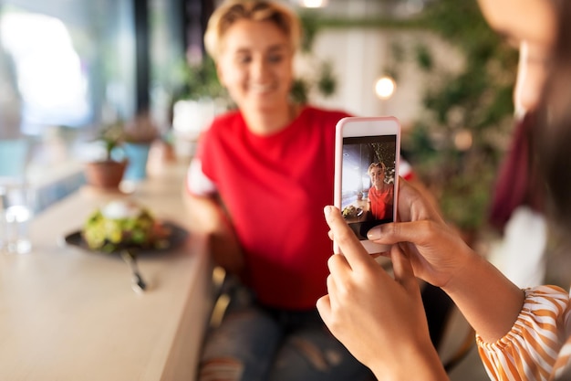 Foto mujeres almorzando y fotografiando en una cafetería