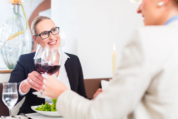 Mujeres en almuerzo de negocios brindando con vino.