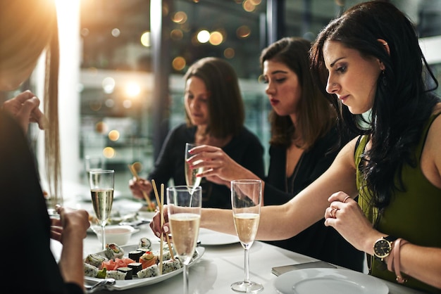 Mujeres amigas cena y restaurante con champán, sushi o brindis para unir la felicidad o la celebración Comida grupal de mujeres y fiesta para cenas elegantes, amistad o conversación en la noche para celebrar