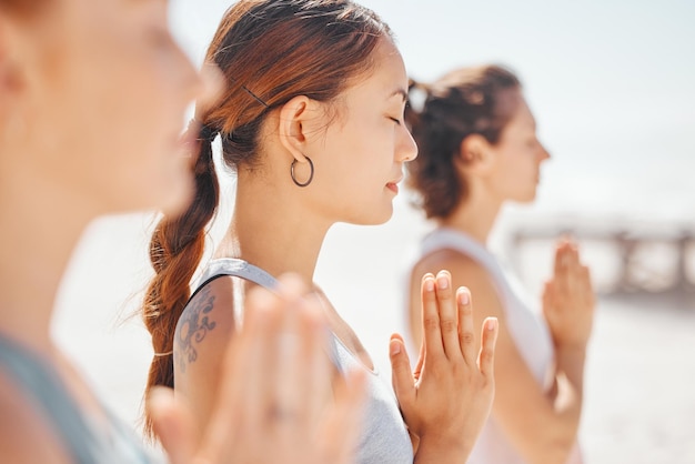 Mujeres amigas meditan mientras entrenan ejercicios de yoga en la playa Grupo de atletas zen que trabajan afuera con equilibrio de paz interior y se vuelven saludables o saludables en un estilo de vida físico