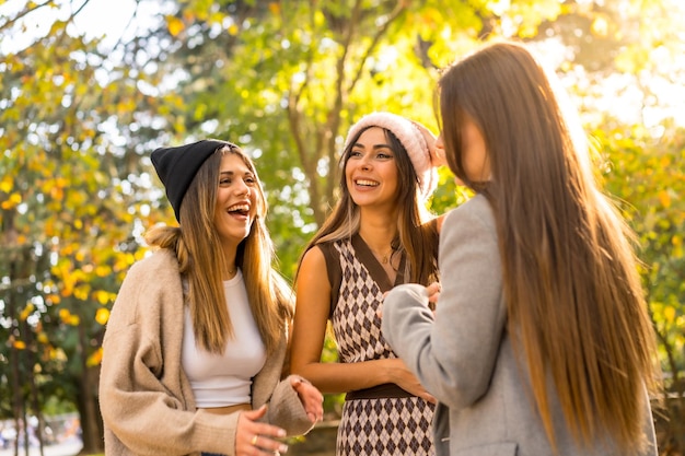 Mujeres amigas sonriendo en un parque en otoño con sombreros de lana estilo de vida de moda de otoño