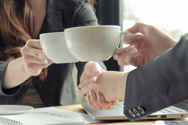 Las mujeres aplauden las tazas de café y chaquean las manos después de finalizar el acuerdo