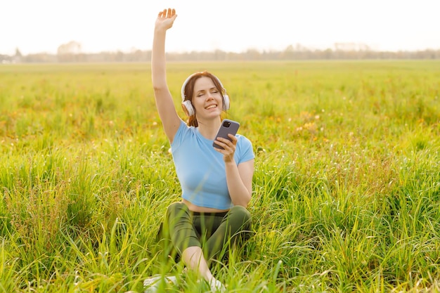 Las mujeres appy con los ojos cerrados escuchan música en auriculares y teléfonos inteligentes rodeadas de naturaleza