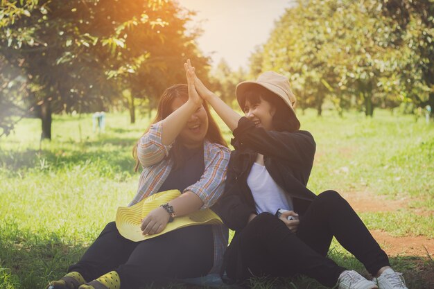 Mujeres de Asia, adolescentes, niñas sentadas en el jardín de frutas con relajarse y feliz.