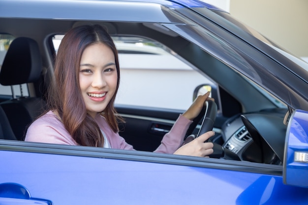 Las mujeres asiáticas conducen un automóvil y sonríen felices con una expresión alegre y positiva durante el viaje en automóvil para viajar, la gente disfruta del transporte de risa y la mujer feliz relajada en concepto de vacaciones de viaje