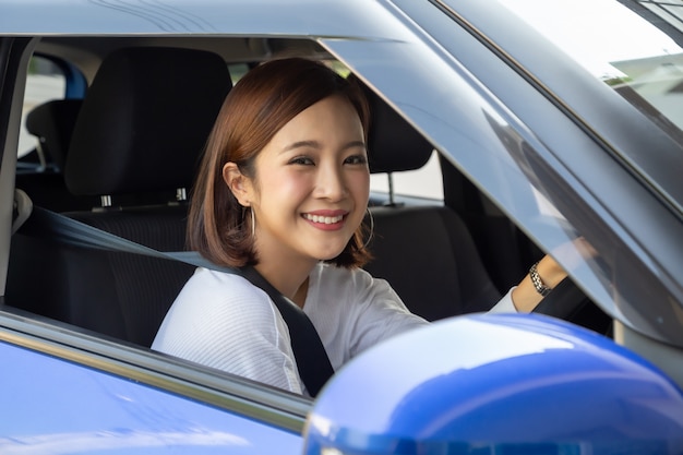 Las mujeres asiáticas conducen un coche tan feliz y sonríen.